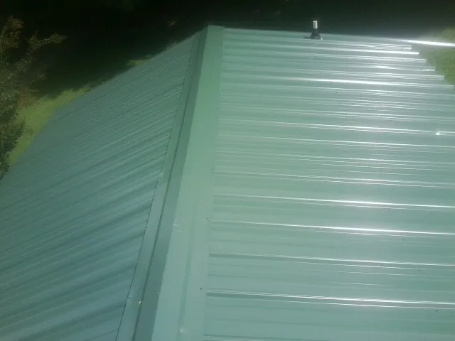 New green metal panels meeting at the ridge of a roof — Flat Roof Repair work by our crew in Hardyville