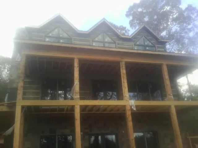 Dormers and porch framing on a large log home under construction — Roof Coating work by our crew in Hardyville