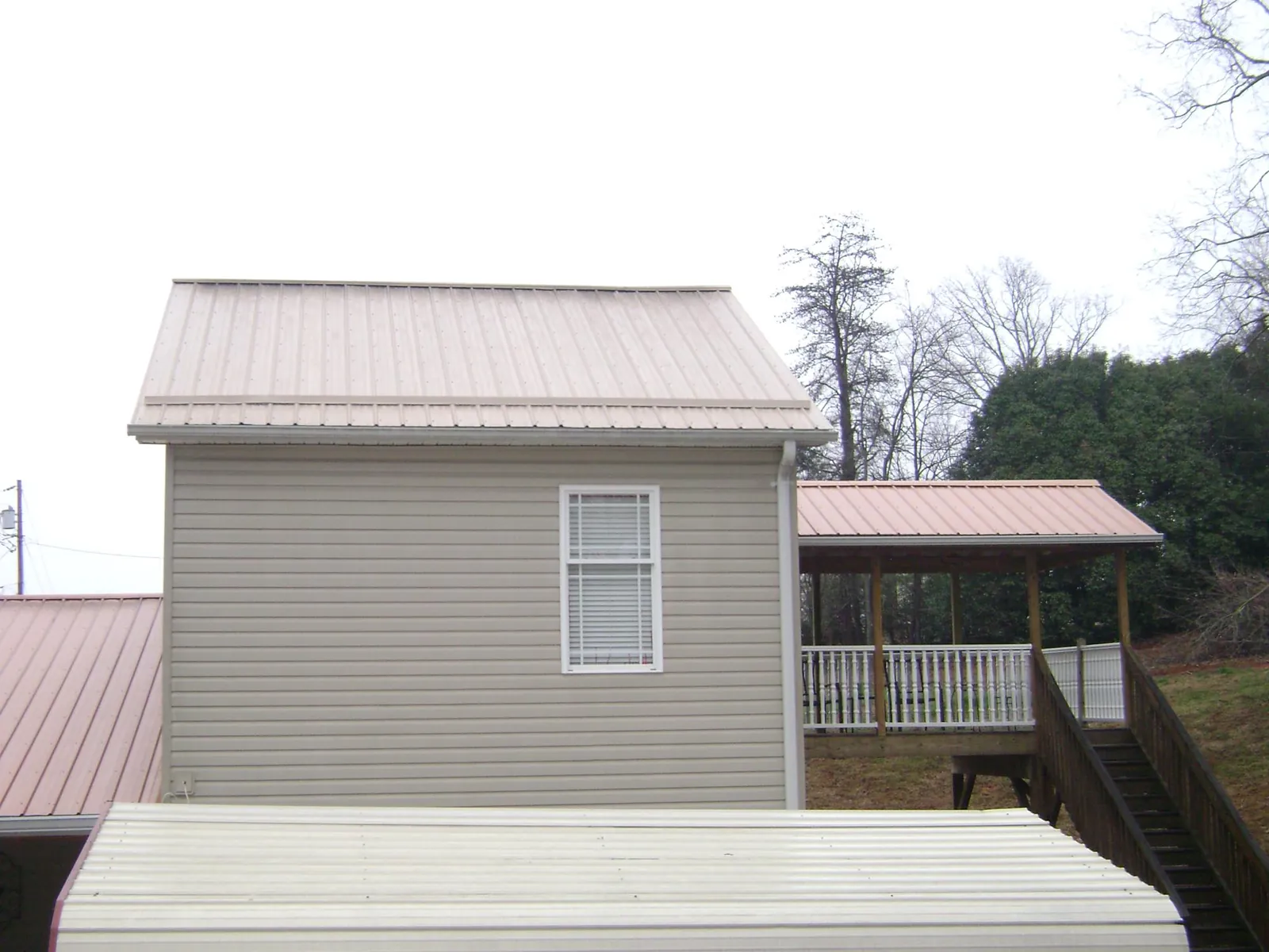 Tan metal roofs on a two story addition and attached porch, from a Roof Replacement job in Hardyville