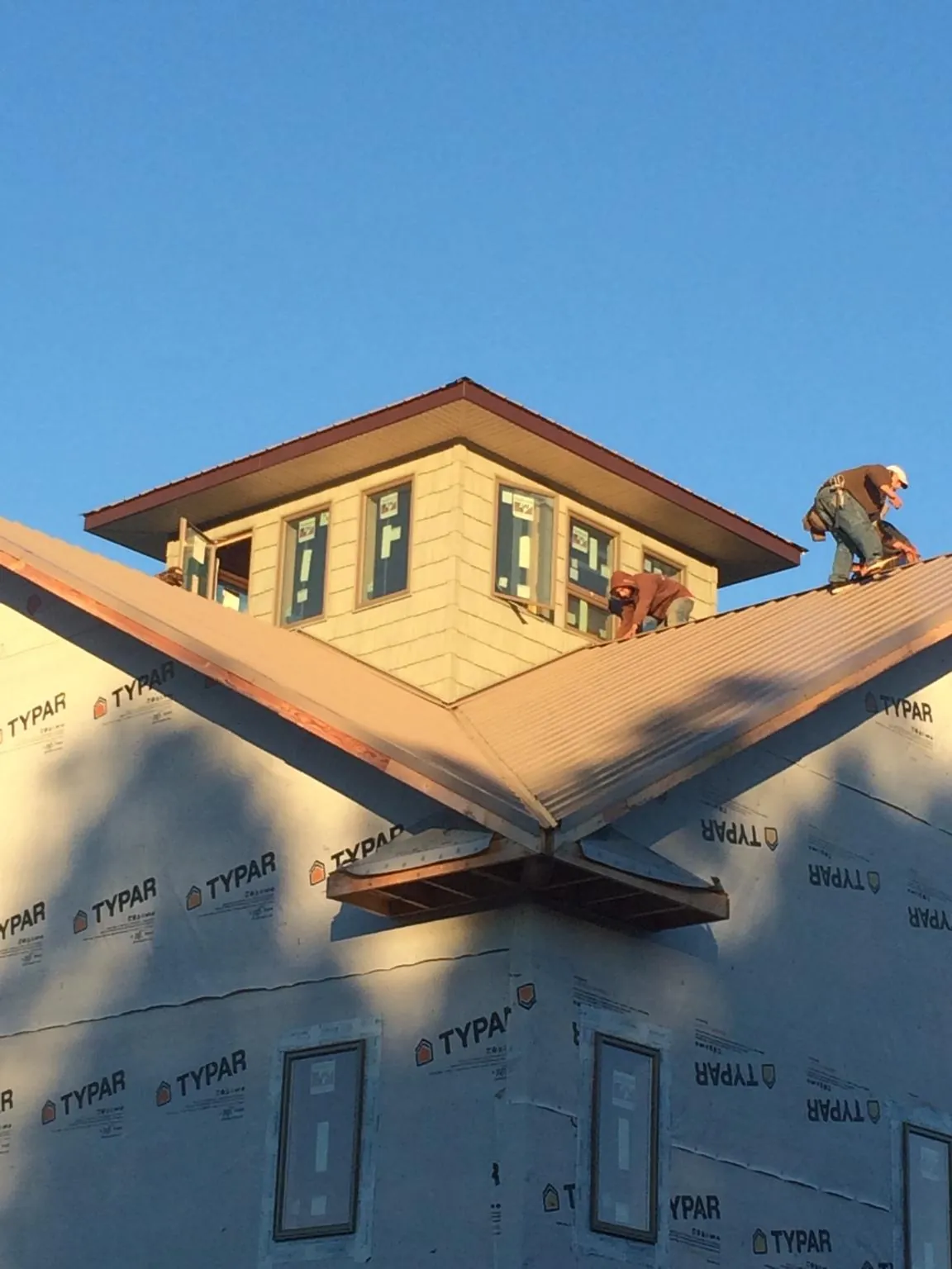 Roofers working around a rooftop cupola on a new metal roof at sunset — Roof Waterproofing in Hardyville by Roofing Brothers